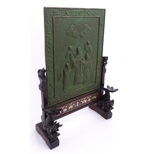 1262 - A Chinese table screen with cast green painted panel having relief decoration depicting an Imperial ... 