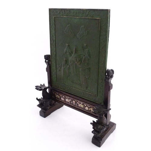 1262 - A Chinese table screen with cast green painted panel having relief decoration depicting an Imperial ... 