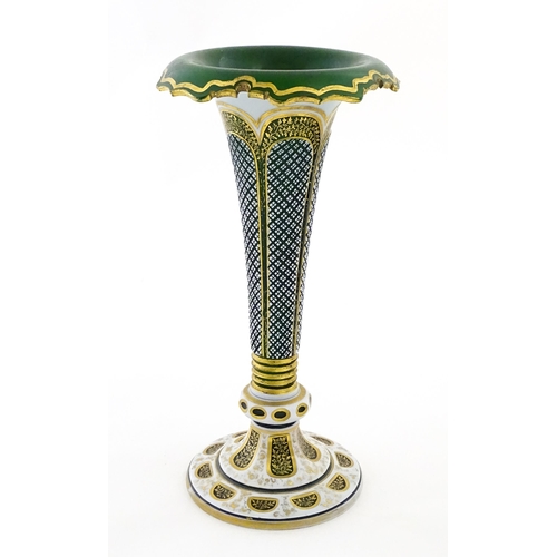 304 - A Bohemian green glass vase of flared form with white overlay and gilt detail. Approx. 12 1/4
