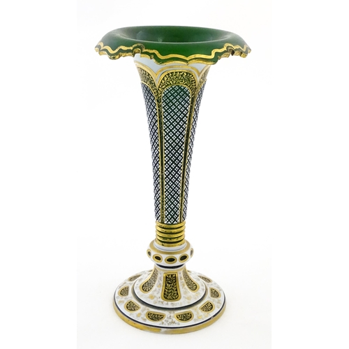 304 - A Bohemian green glass vase of flared form with white overlay and gilt detail. Approx. 12 1/4