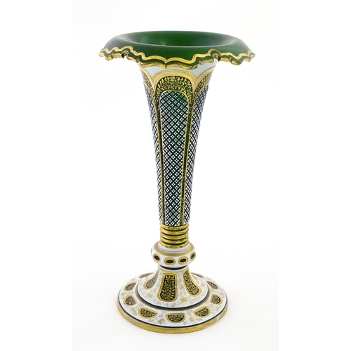 304 - A Bohemian green glass vase of flared form with white overlay and gilt detail. Approx. 12 1/4
