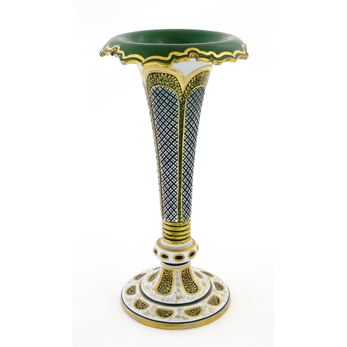 304 - A Bohemian green glass vase of flared form with white overlay and gilt detail. Approx. 12 1/4