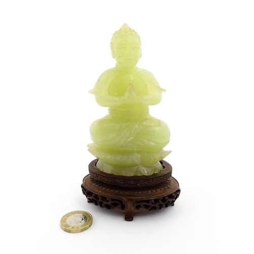 1023 - A Chinese jade coloured soapstone carving modelled as a seated Buddha with hands in prayer on a styl... 