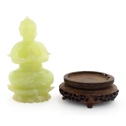 1023 - A Chinese jade coloured soapstone carving modelled as a seated Buddha with hands in prayer on a styl... 