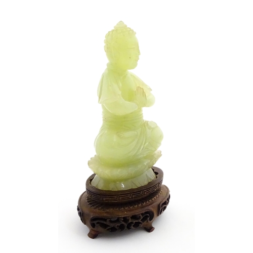 1023 - A Chinese jade coloured soapstone carving modelled as a seated Buddha with hands in prayer on a styl... 