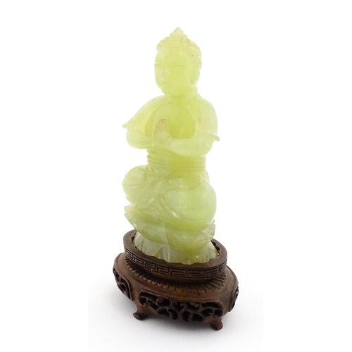 1023 - A Chinese jade coloured soapstone carving modelled as a seated Buddha with hands in prayer on a styl... 