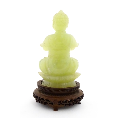 1023 - A Chinese jade coloured soapstone carving modelled as a seated Buddha with hands in prayer on a styl... 