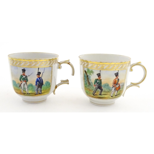 222 - Two Polish Korzec tea cups and saucers with hand painted decoration depicting 18thC Infantry soldier... 