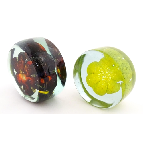 331 - Two Mdina glass paperweights with flower detail. Both signed under. Largest approx. 4 1/2