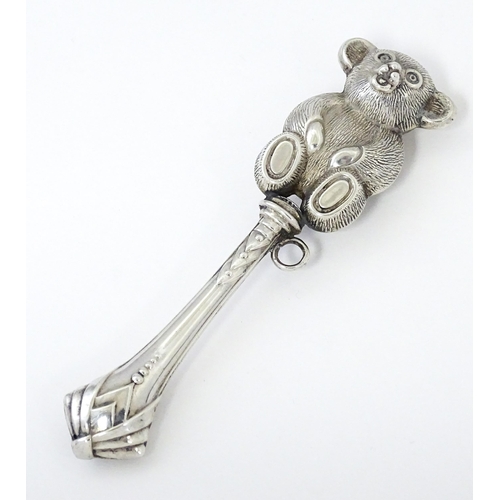 351 - A white metal child's rattle with teddy bear decoration. Approx. 4 1/2