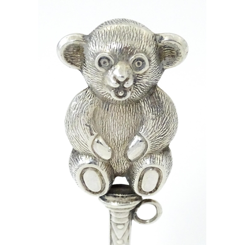 351 - A white metal child's rattle with teddy bear decoration. Approx. 4 1/2