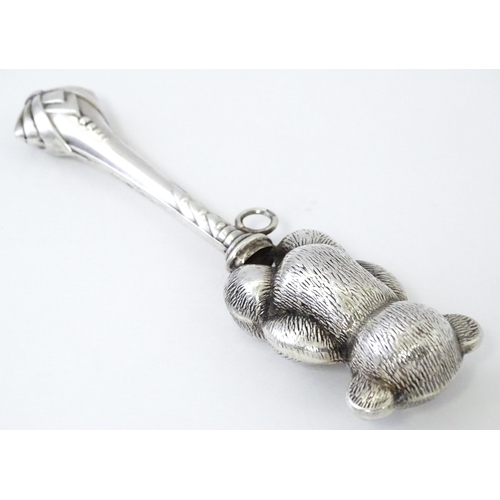 351 - A white metal child's rattle with teddy bear decoration. Approx. 4 1/2