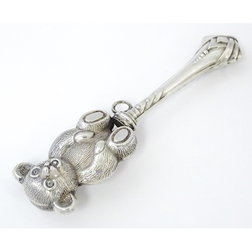 351 - A white metal child's rattle with teddy bear decoration. Approx. 4 1/2