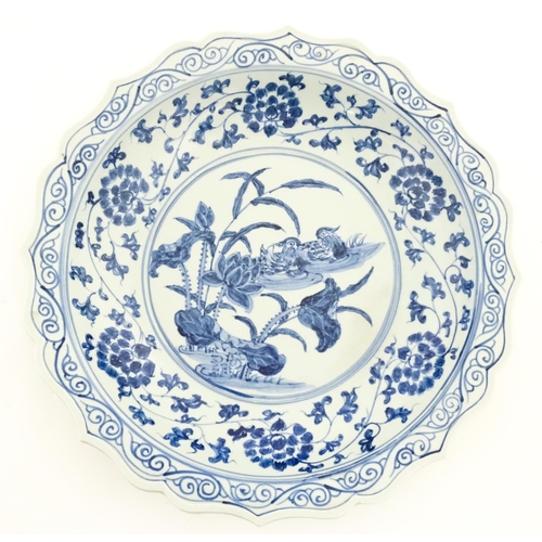 63 - A Chinese blue and white charger decorated with ducks and lotus flowers with scrolling foliate borde... 