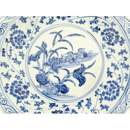 63 - A Chinese blue and white charger decorated with ducks and lotus flowers with scrolling foliate borde... 