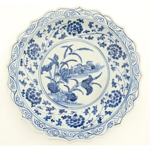 63 - A Chinese blue and white charger decorated with ducks and lotus flowers with scrolling foliate borde... 