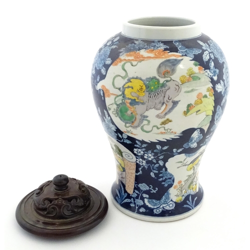 20 - A Chinese blue and white vase with carved hardwood lid, decorated with flowers and butterflies with ... 