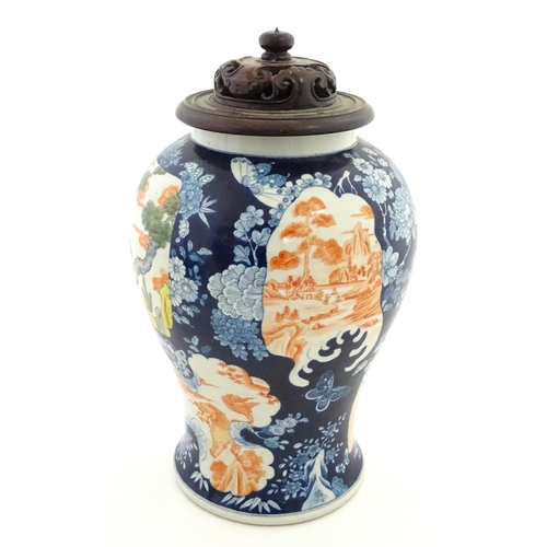 20 - A Chinese blue and white vase with carved hardwood lid, decorated with flowers and butterflies with ... 