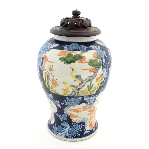 20 - A Chinese blue and white vase with carved hardwood lid, decorated with flowers and butterflies with ... 