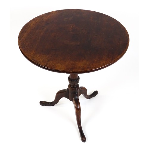 25 - A Georgian mahogany tripod table with a circular top above a turned pedestal and raised on three cab... 