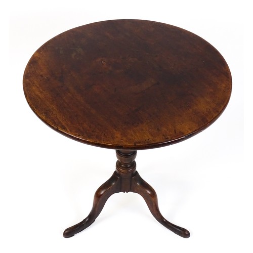 25 - A Georgian mahogany tripod table with a circular top above a turned pedestal and raised on three cab... 