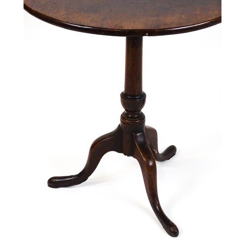 25 - A Georgian mahogany tripod table with a circular top above a turned pedestal and raised on three cab... 