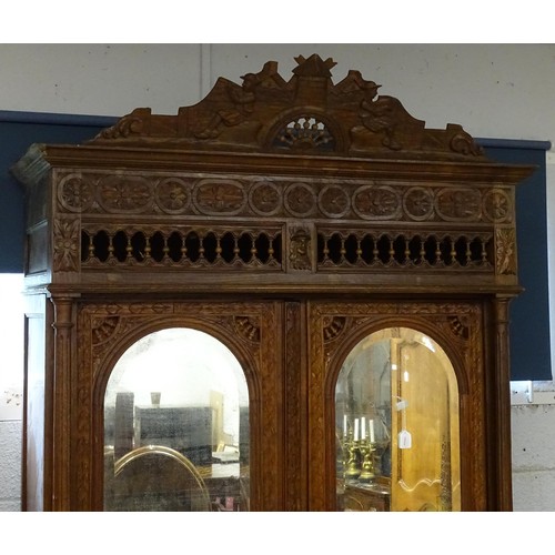 35 - A late 19thC Breton style armoire with carved floral decoration and carved masks with turned finials... 