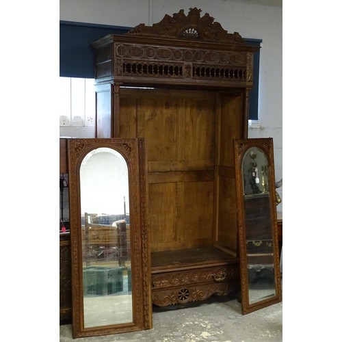 35 - A late 19thC Breton style armoire with carved floral decoration and carved masks with turned finials... 