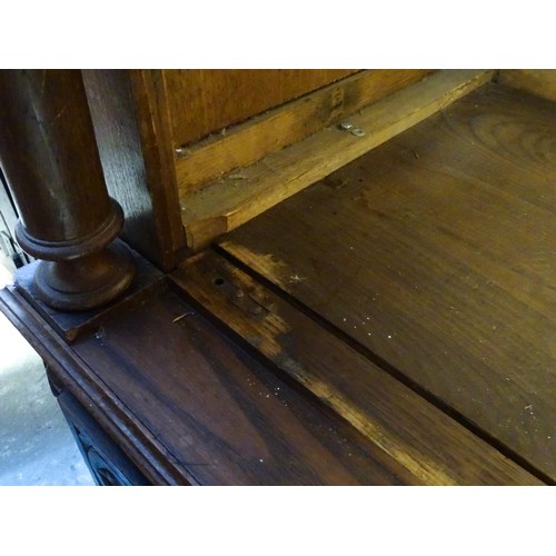 35 - A late 19thC Breton style armoire with carved floral decoration and carved masks with turned finials... 