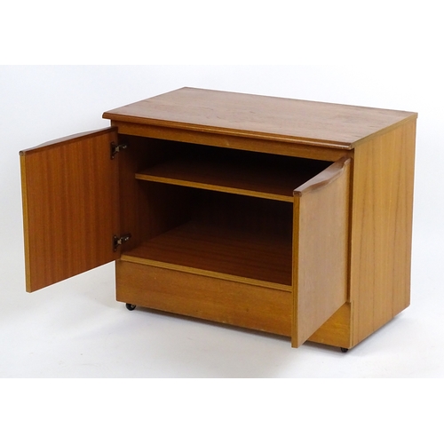 21 - Vintage / Retro: A teak two door cabinet raised on castors. 29 1/2