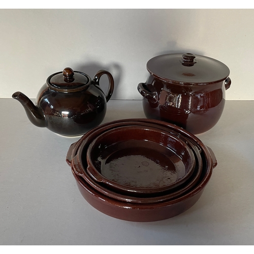 117 - A quantity of brown glazed ceramics - flan dishes, teapot and casserole dish. Largest dish 18 cms di... 