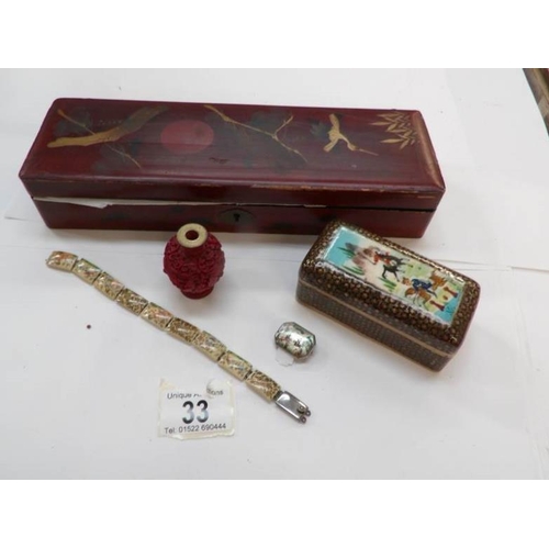 33 - An oriental lacquered box and contents to include hand painted mother of pearl and silver brooch, ha... 