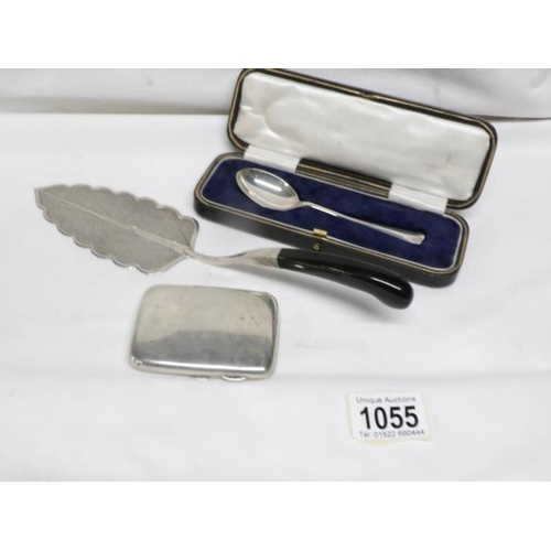 1055 - A silver cigarette case, a silver cased spoon and a white metal cake slice