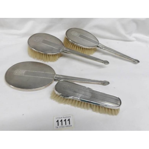 1111 - A silver backed hand mirror and 3 matching brushes