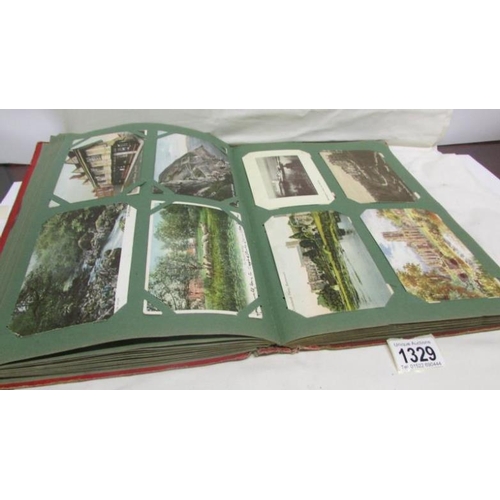 1329 - A red postcard album containing in excess of 250 postcards including Landscapes, Bamforth, Greeting ... 