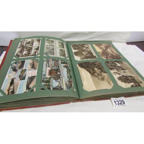 1329 - A red postcard album containing in excess of 250 postcards including Landscapes, Bamforth, Greeting ... 