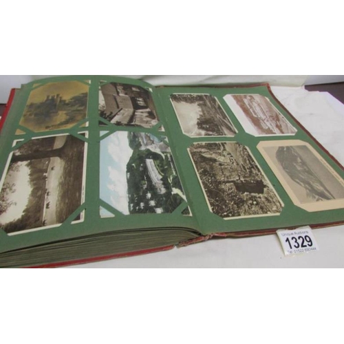 1329 - A red postcard album containing in excess of 250 postcards including Landscapes, Bamforth, Greeting ... 