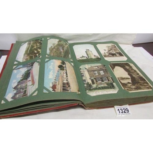 1329 - A red postcard album containing in excess of 250 postcards including Landscapes, Bamforth, Greeting ... 