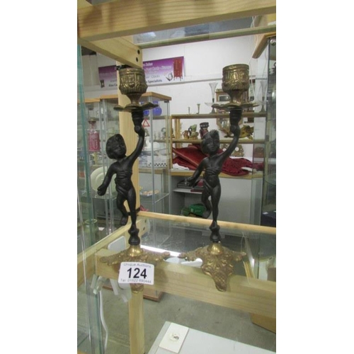 124 - A pair of cherub candlesticks with brass mounts