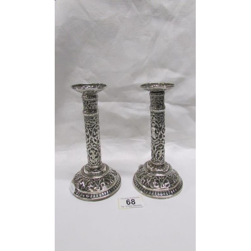 68 - A pair of ornate Indian silver candlesticks