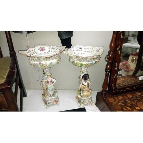 392 - A pair of porcelain figures supporting flower encrusted bowls