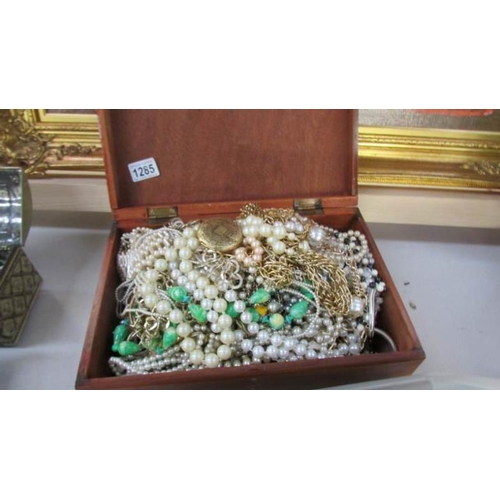 1285 - A large wooden box of costume jewellery