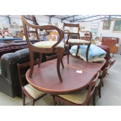 439 - An extending mahogany dining table with protective cover and 8 brass inlaid dining chairs