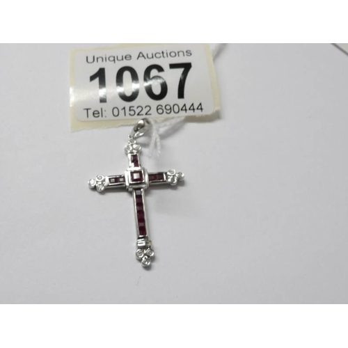 1067 - A 9ct white gold diamond and ruby set cross pendant