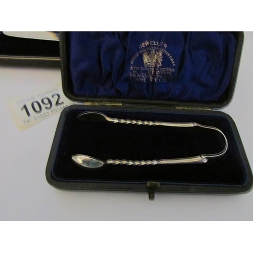 1092 - A cased set of 6 silver handled butter knives (H M Sheffield 1904-06) and a cased silver sugar nips ... 