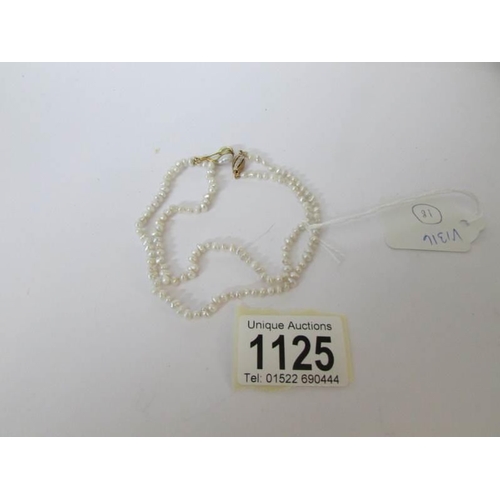 1125 - A single row of pearls with a diamond and 18ct gold clasp