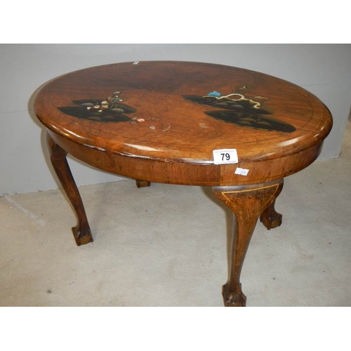 79 - A small oval mahogany table with lacquered pictures, on ball and claw feet, in fair condition.