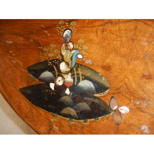 79 - A small oval mahogany table with lacquered pictures, on ball and claw feet, in fair condition.