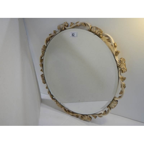 82 - A carved wood guesso and guilded bevel edged circular mirror, no damage.