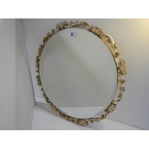 82 - A carved wood guesso and guilded bevel edged circular mirror, no damage.